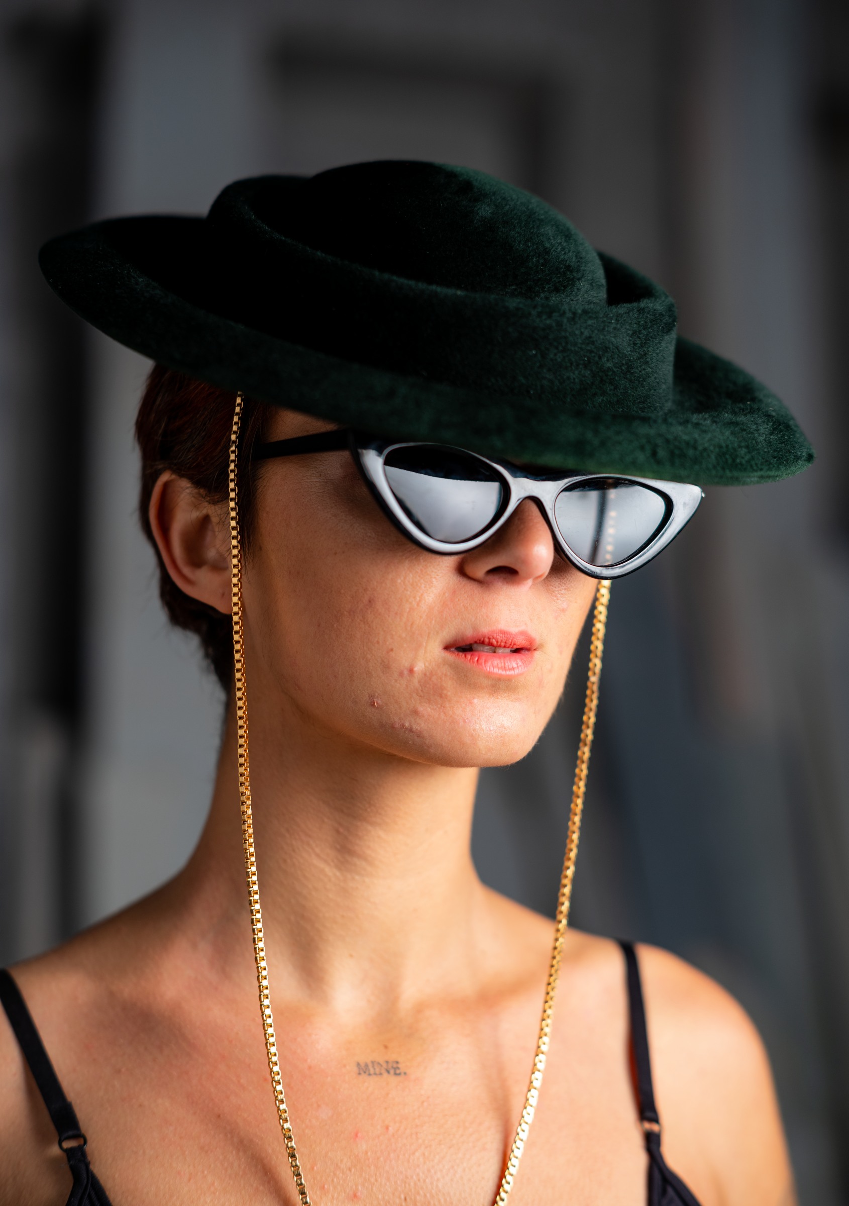 Close portrait of a woman wearing a sculptural green hat and sunglasses
